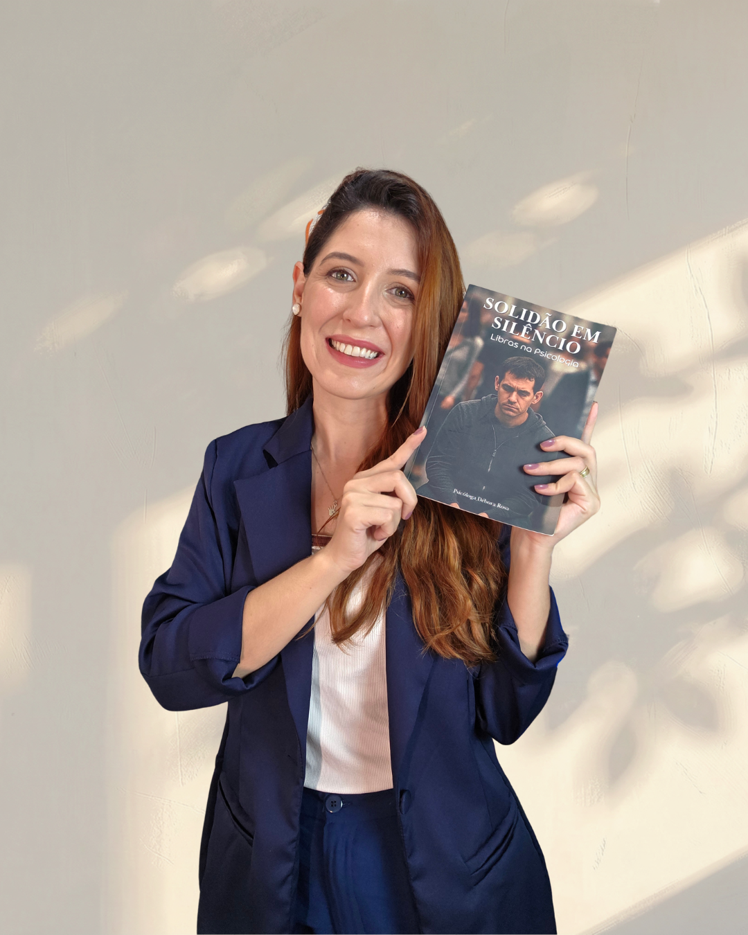 Psicóloga Débora Rosa segurando o livro Solidão em Silêncio - Libras na Psicologia